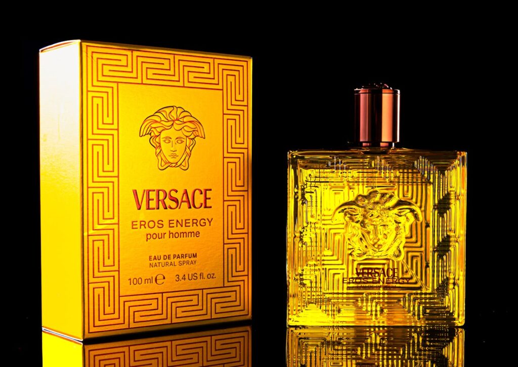 Intricately designed Versace Eros Energy perfume bottle with matching box on a dark background.